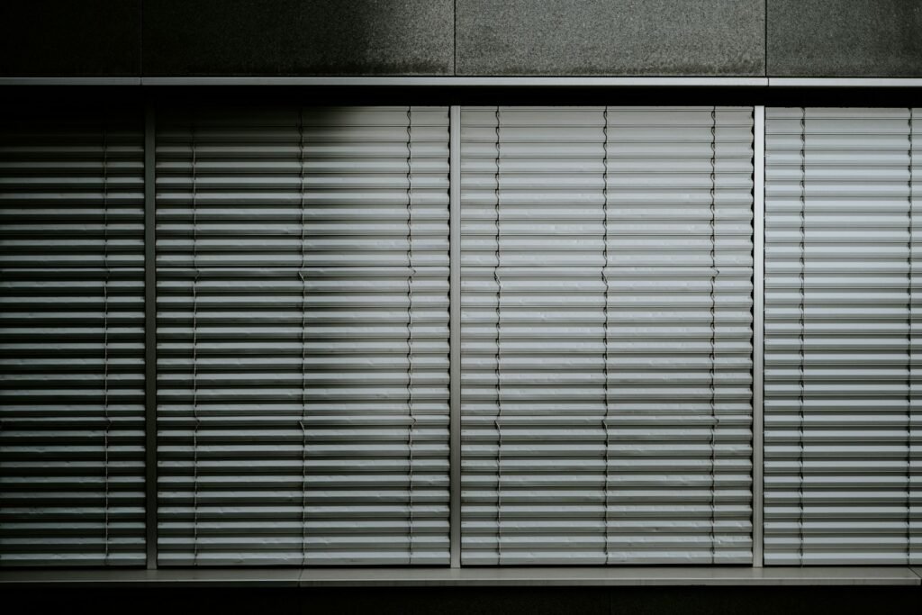 a black and white photo of a window with blinds